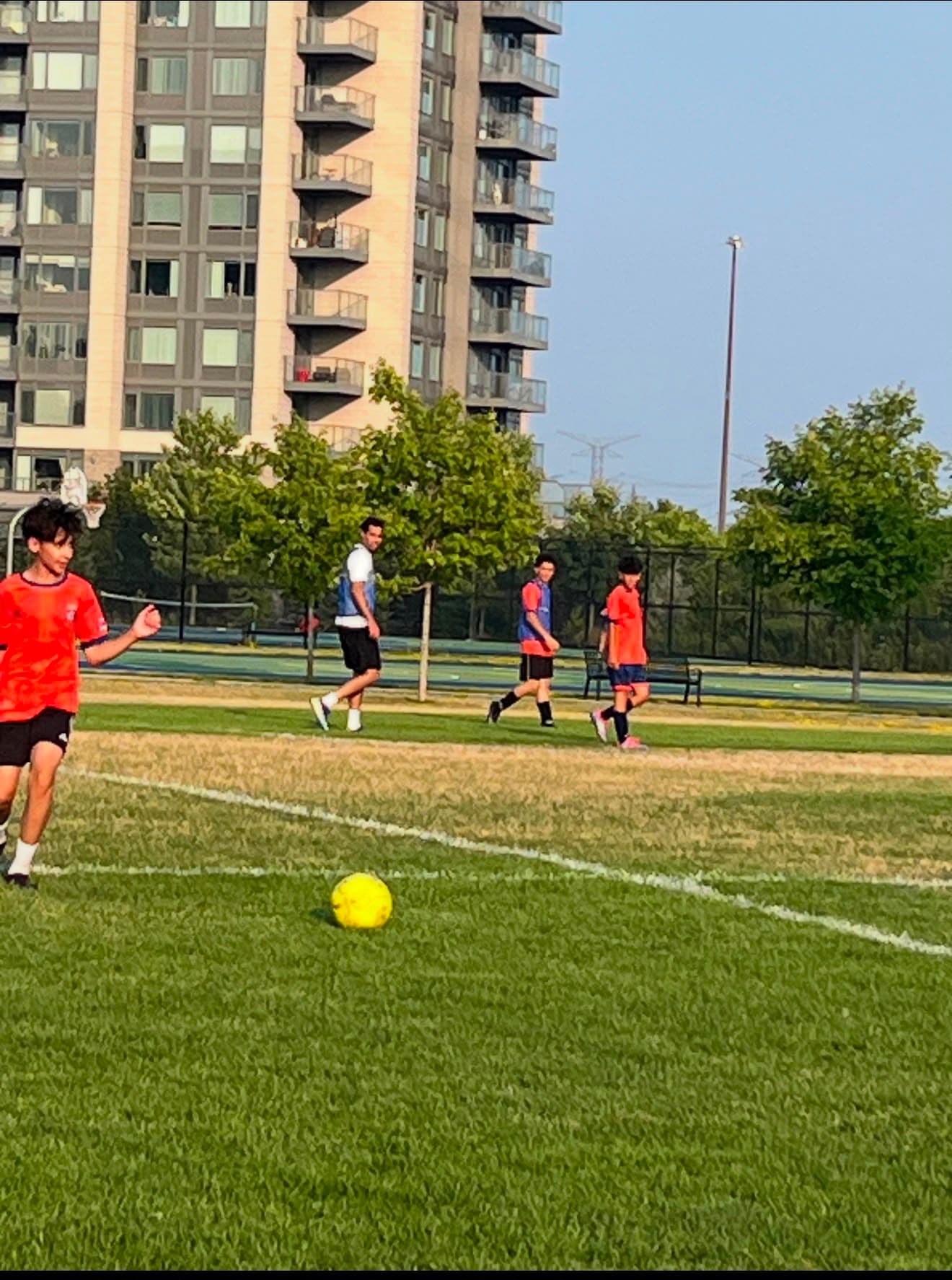 Children sprint across a community football pitch in Toronto during an after-school session