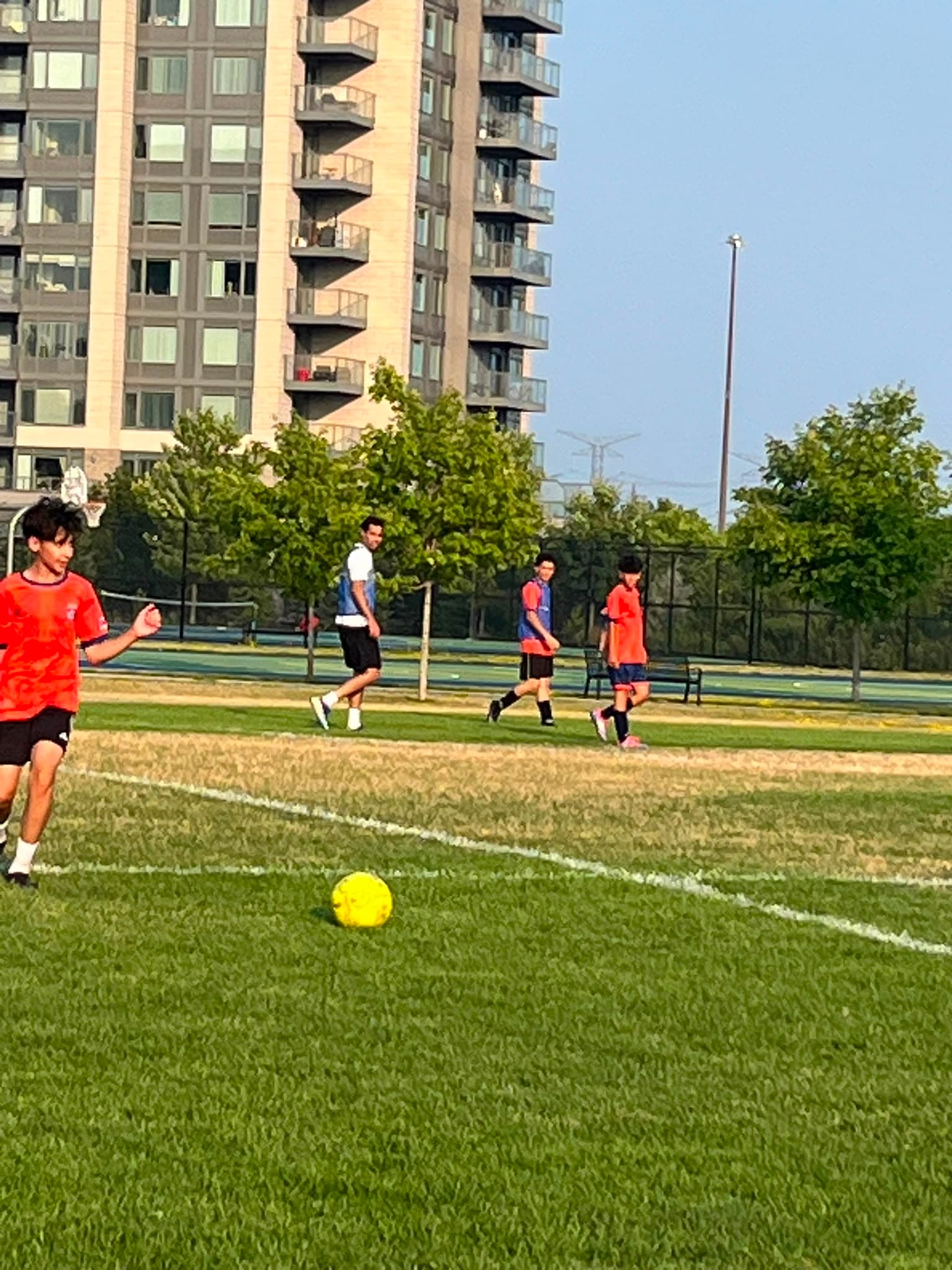 Young footballers train on a grass pitch in a Toronto park